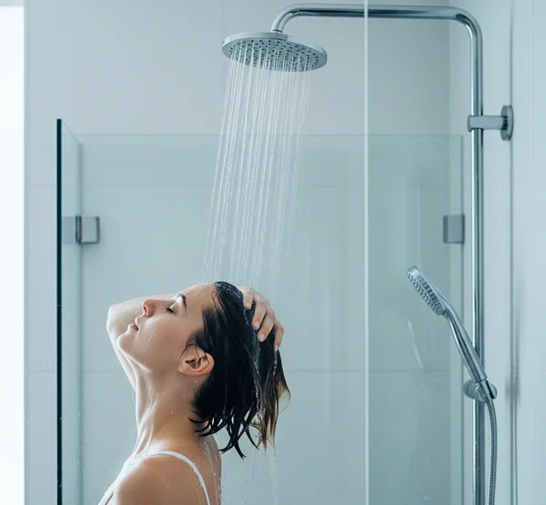 Person rinsing hair thoroughly in a shower, avoiding face.